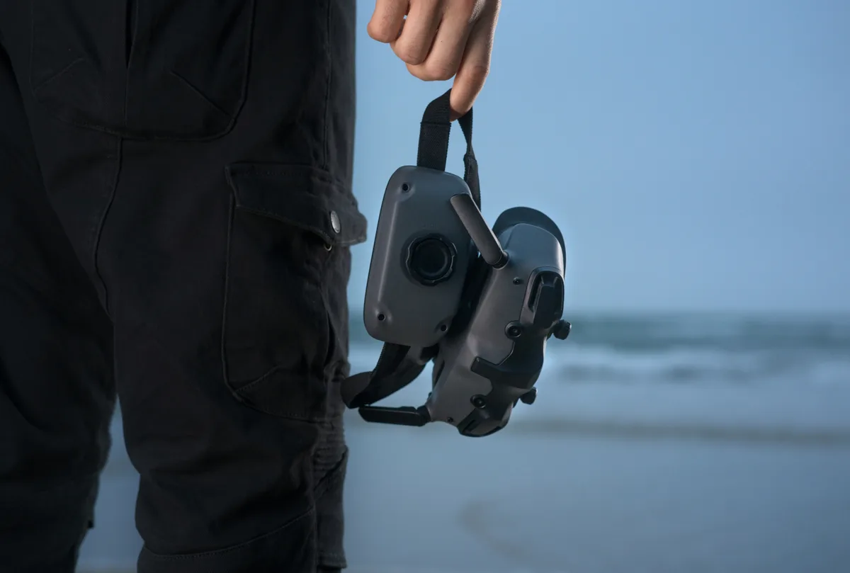 DJI Goggles 3 FPV goggles carried by their strap at the beach